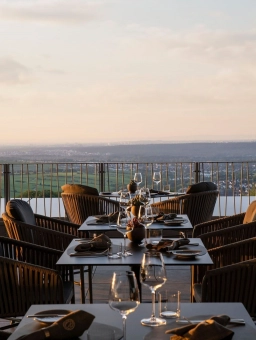Auf einer Terrasse vom Hotel im Rheingau stehen mehrere gedeckte Tische in der Abenddämmerung