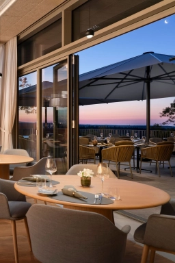 Ein gedeckter Tisch im Restaurant mit der großen Außenterrasse mit schöner Aussicht im Hintergrund