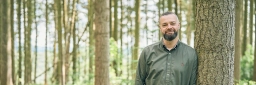 Foto von Falk Richter, Küchenchef eines Restaurants im Rheingau, der lässig an einem Baumstamm angelehnt ist