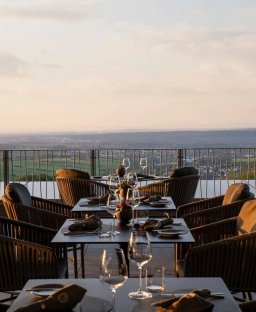 Auf einer Terrasse vom Hotel im Rheingau stehen mehrere gedeckte Tische in der Abenddämmerung