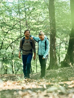 Ein Mann und eine Frau wandern auf einem Waldweg durch einen Wald und entdecken die Sehenswürdigkeiten des Rheingaus
