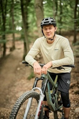 Foto von einem Mountainbikefahrer mit Sportklamotten und Helm, der auf einem MTB Trail in Hessen posiert