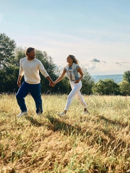 Nahe eines Sporthotels im Rheingau laufen eine Mann und eine Frau Händchen haltend über eine Wiese