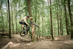 Ein Mountainbiker macht einen Sprung auf der Crossstrecke im Wald