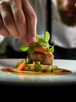 In einer Hochzeitslocation im Rheingau verziert eine Hand eine appetitliche Vorspeise mit einem grünen Pflänzchen