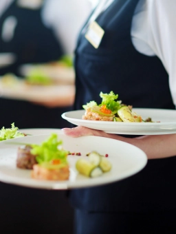 A waitress carries several plates of delicious appetisers as part of her hotel job near Frankfurt