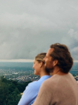A man and a woman hold each other in their arms and gaze out over the vast landscape during their holiday in the Rheingau