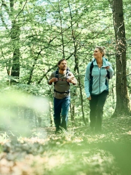 Ein Mann und eine Frau in Sportklamotten wandern einen Waldweg im Rheingau entlang