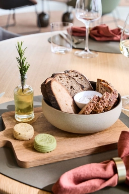 Ein Brotkorb mit Dips ist auf einem Holzbrett im Restaurant mit Aussicht platziert